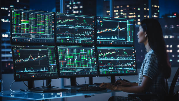 Financial Analyst Working on a Computer with Multi-Monitor Workstation with Real-Time Stocks, Commodities and Exchange Market Charts. Businesswoman at Work in Investment Broker Agency Office at Night. Financial Analyst Working on a Computer with Multi-Monitor Workstation with Real-Time Stocks, Commodities and Exchange Market Charts. Businesswoman at Work in Investment Broker Agency Office at Night. hedge fund stock pictures, royalty-free photos & images