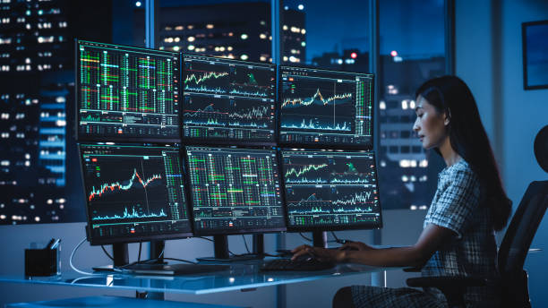 istock Financial Analyst Working on a Computer with Multi-Monitor Workstation with Real-Time Stocks, Commodities and Exchange Market Charts. Businesswoman at Work in Investment Broker Agency Office at Night. 1358049854