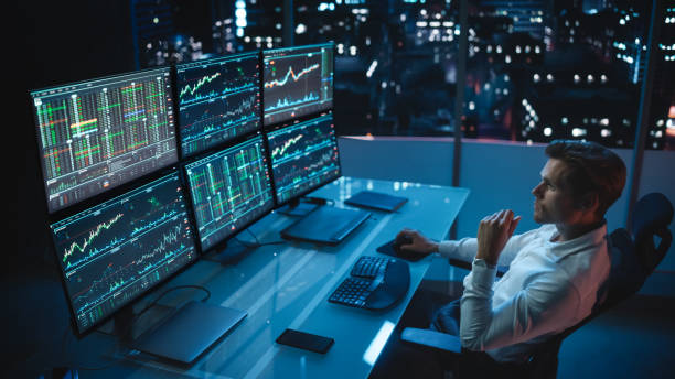 Financial Analyst Working on a Computer with Multi-Monitor Workstation with Real-Time Stocks, Commodities and Foreign Exchange Charts. Businessman Works in Investment Bank City Office Late Evening. Financial Analyst Working on a Computer with Multi-Monitor Workstation with Real-Time Stocks, Commodities and Foreign Exchange Charts. Businessman Works in Investment Bank City Office Late Evening. stock trader stock pictures, royalty-free photos & images
