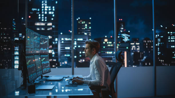 istock Financial Analyst Working on Computer with Multi-Monitor Workstation with Real-Time Stocks, Commodities and Exchange Market Charts. Businessman Deliberating on Next Investment Trade in a Bank Office. 1358050702