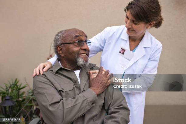 Caregiver Talking With Senior Man Against Wall Stock Photo - Download Image Now - Hand On Shoulder, Support, 70-79 Years