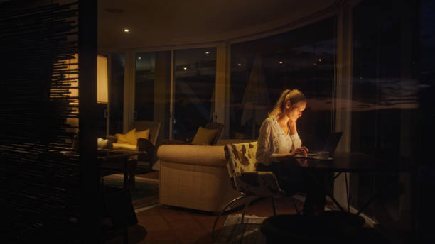 istock Businesswoman working late from home. Looking at smart phone and computer screen 1358052685