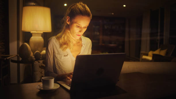 istock Businesswoman working late from home. Looking at commputer screen, drinking coffee 1358052686
