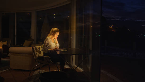 istock Businesswoman working late from home. Looking at smart phone and computer screen 1358052722