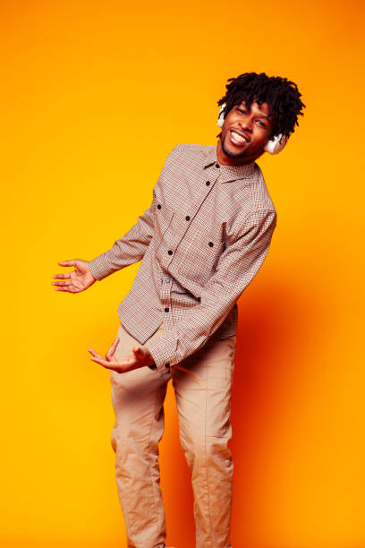 istock young handsome african american guy student posing cheerful and gesturing on yellow background, lifestyle people concept 1358053058