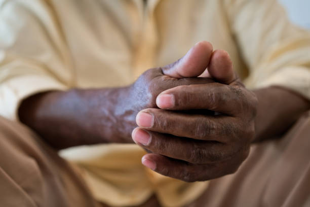 istock Senior man with hands clasped sitting in living room 1358055100