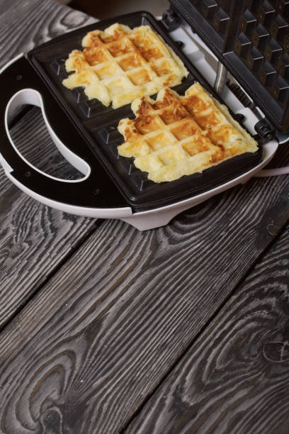 istock Waffle maker with waffles. On black pine boards. Close-up shot. 1358057074