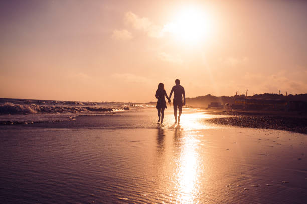 istock Silhouette Couple Walking On Beach Against Sky During Sunset 1358058440