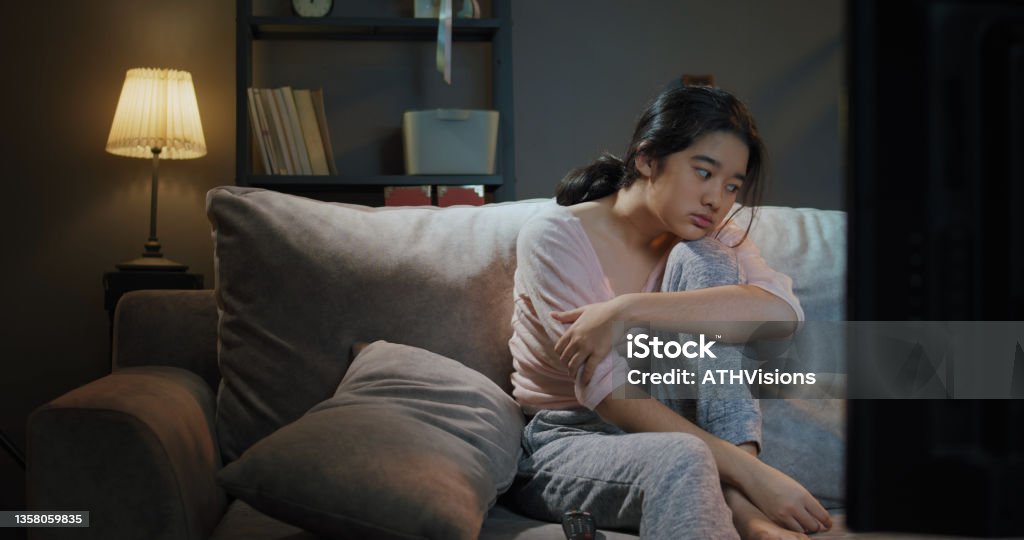 Close-up Teenager Boring while watching tv at home in the night time. Asian Teenager Boring while watching tv at home in the nighttime. Insomnia Stock Photo