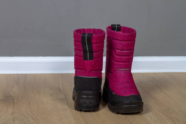 bottes d’hiver bottes de neige rose foncé avec semelles noires sur le sol dans la chambre - apres ski photos photos et images de collection