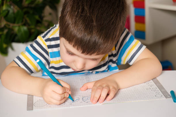 istock Preschool child learns to write, writes copybook. 1358063795