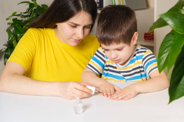 mama trägt bitteren nagellack auf die nägel des jungen auf, um ihn von der schlechten angewohnheit zu befreien, seine nägel zu beißen - bad habit fear emotional stress women stock-fotos und bilder