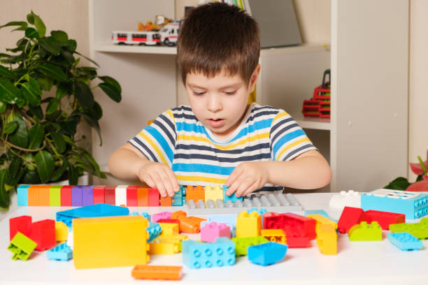 istock A 4-year-old boy in a striped T-shirt plays with multi-colored bricks of the constructor. Kindergarten children's educational games. 1358064205