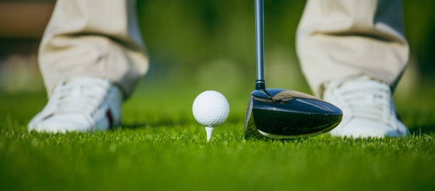 bola de golfe no tee no curso de grama de turf, golfista batendo pelo motorista do clube de golfe. close-up de sapatos de golfe branco - golf swing golf golf club golf ball - fotografias e filmes do acervo