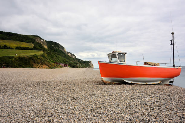 A shingle beach at Branscombe in South Devon, with a fishing boat moored for refurbishment.