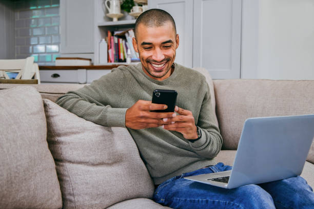 istock Shot of a young man using his smartphone and laptop while working from home 1358069677