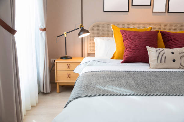 istock Red and brown tone pillow bedding in modern bedroom interior with lamp on table. 1358070658