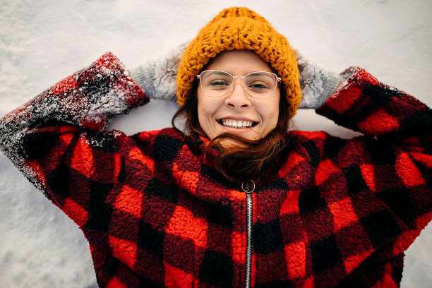 Woman is lying on the snow and looking at the camera
