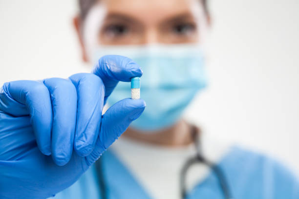 istock Female UK NHS GP ICU general practitioner doctor wearing protective face mask holding antibiotic pill 1358071171