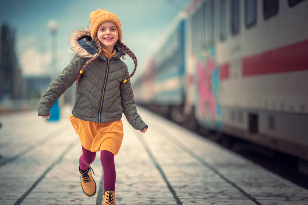 Happy little girl traveler with backpack in the railway train station. Kid traveler tourist happy running at train station. stock photo