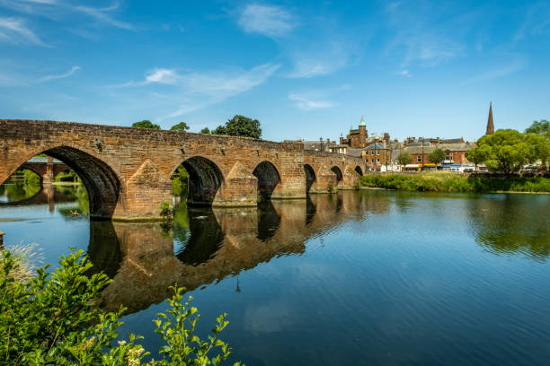 The Medieval Devorgilla Bridge with its gothic arches, reflecting on the River Nith during a summers day in Dumfries, Scotland stock photo