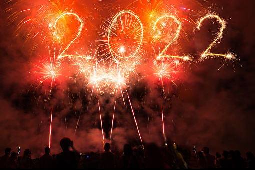 People celebrate new year`s eve, text 2022 of sparklers 2022 and Sparkle firework in the sky.