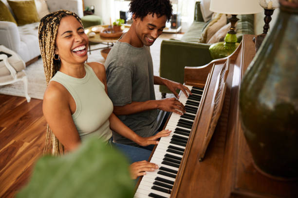 istock Woman laughing while playing piano with her boyfriend at home 1358077896