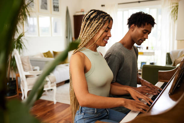 istock Young couple smiling while playing the piano at home 1358078181