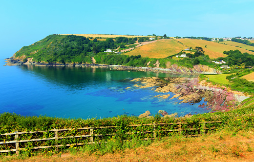 Talland Bay Cornwall UK with colourful red and purple rocks and clear sea