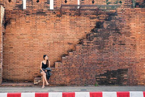 Attractive asian woman sitting on brick wall stairs in Tha Phae Gate at Chiang Mai, Thailand