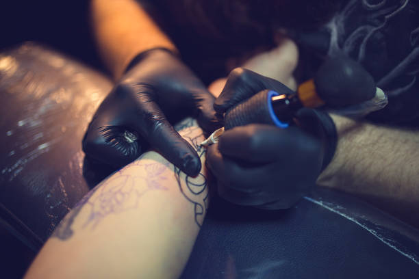 istock Tattoo artist makes a tattoo on a man's hand 1358080244