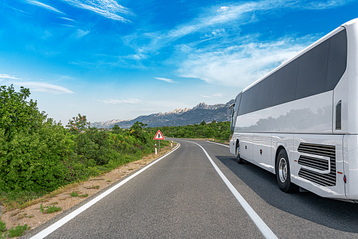 White passenger bus on the highway against the backdrop of a beautiful landscape.