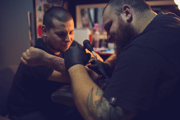 istock Tattoo artist makes a tattoo on a man's hand 1358081440