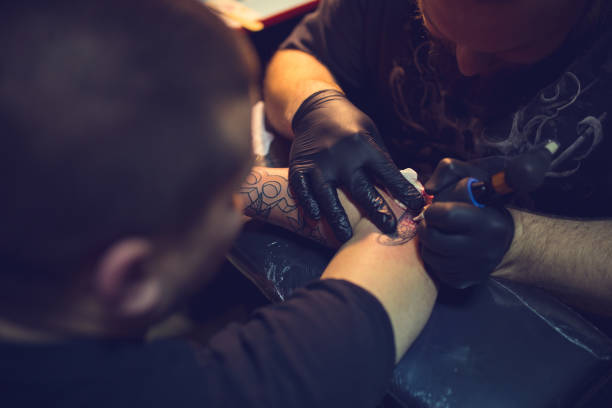 istock Artist making tattoo on customer's hand 1358082449