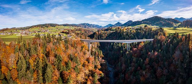 Aerial view of a bridge above a canyon with a village on the left side and mountains in the background. Vorarlberg, Lingenau