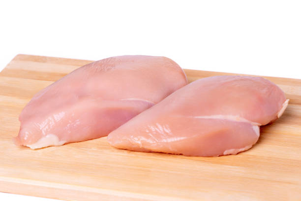 istock Raw chicken breast on a cutting board, white background 1358085792