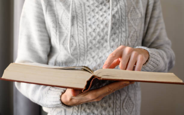 istock Close-up of a man reading into a huge old book. 1358086419