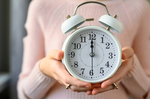 White alarm clock in children's hands close-up