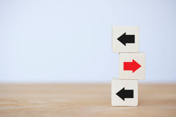 istock Wooden block with red arrow facing the opposite direction  black, arrow, think different individual and standing out of order from the crowd concept on table background. 1358089046