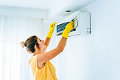 Woman Cleaning Air Conditioning System stock photo