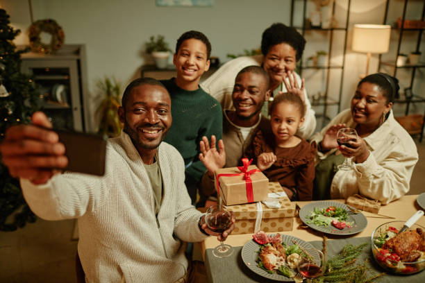 African American Family Taking Selfie at Christmas High angle portrait of happy African-American family taking selfie photo while enjoying Christmas at home together dinner party photos stock pictures, royalty-free photos & images