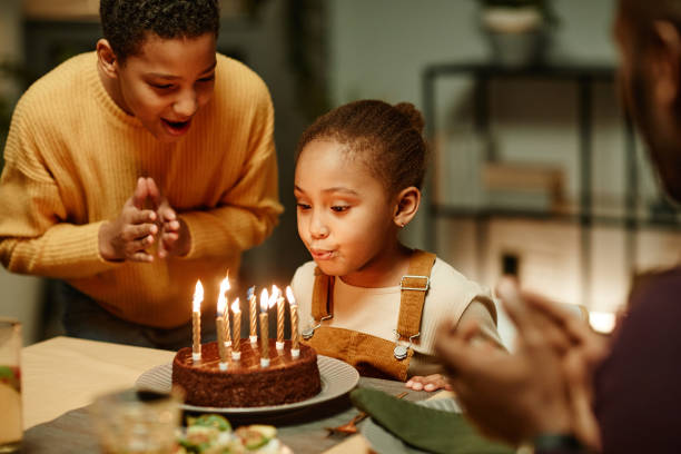 istock Little Girl Blowing Candles 1358090928