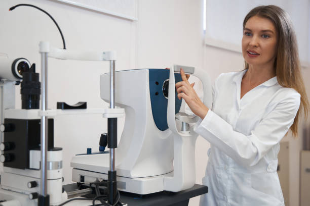 istock Female oculist pointing at forehead rest of autorefractor 1358091645