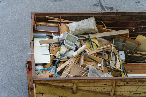 Many old home appliances and furniture in garbage container.