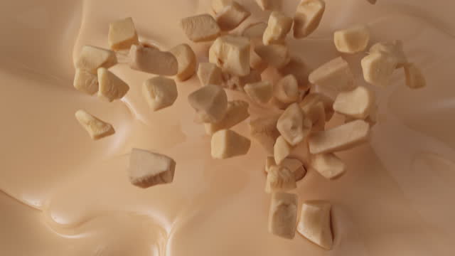 hazelnut pieces falling into white chocolate