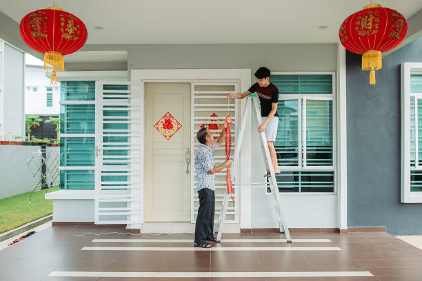 Asian chinese father passing modern fire crackers lighting to son in front yard of their house during chinese new year's eve stock photo