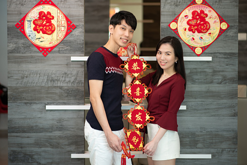 waist up shot of couple looking camera and holding chinese ornaments