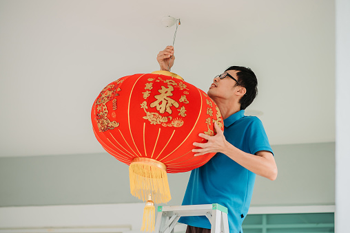 waist up shot of men hands holding traditional chinese red lanterns with ladder