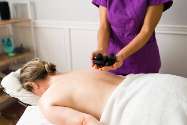 femme massant avec des pierres chaudes - lastone therapy spa treatment massaging massage therapist photos et images de collection