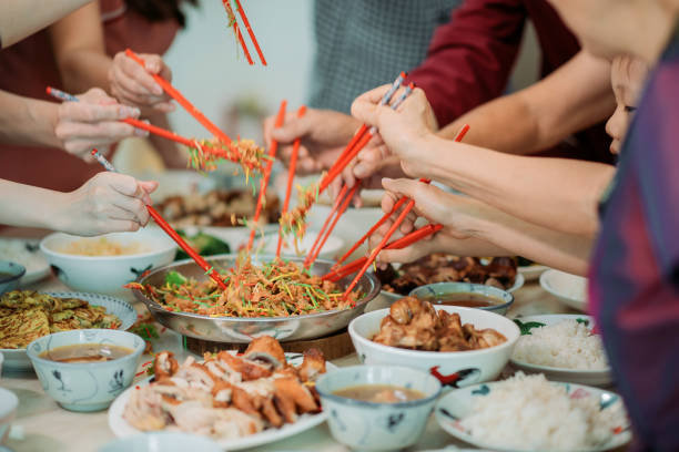 Asian chinese family celebrating chinese new year's eve with raw fish salad “Yusheng” during reunion dinner stock photo